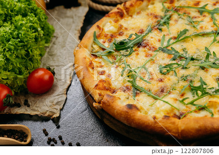 Gourmet four-cheese pizza with arugula, served on a wooden board in a stylish restaurant setting Gourmet four-cheese pizza with arugula, served on a wooden board in a stylish restaurant setting 122807806