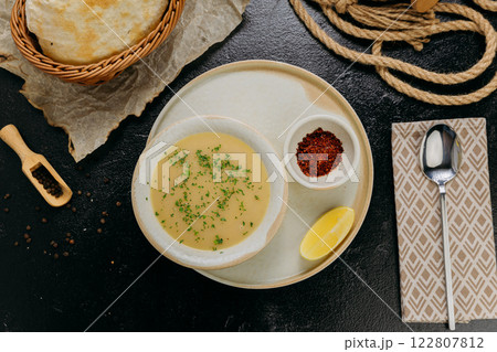Creamy lentil soup with flatbread, sesame seeds, chili flakes, and lemon, served in an elegant style Creamy lentil soup with flatbread, sesame seeds, chili flakes, and lemon, served in an elegant style 122807812
