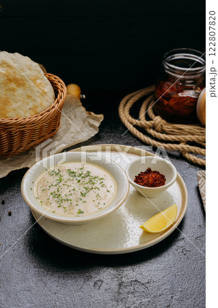 Creamy lentil soup with flatbread, sesame seeds, chili flakes, and lemon, served in an elegant style Creamy lentil soup with flatbread, sesame seeds, chili flakes, and lemon, served in an elegant style 122807820