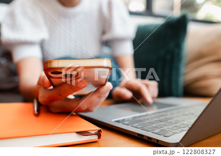 Person multitasking with smartphone and laptop, highlighting modern technology and remote work or study. Person multitasking with smartphone and laptop, highlighting modern technology and remote work or study. 122808327