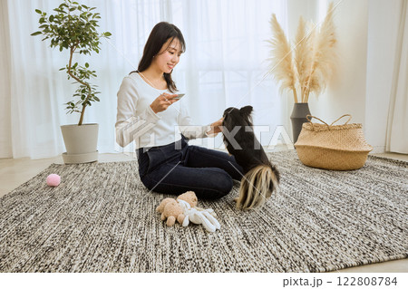 リビングで愛犬と遊ぶ女性 リビングで愛犬と遊ぶ女性 122808784