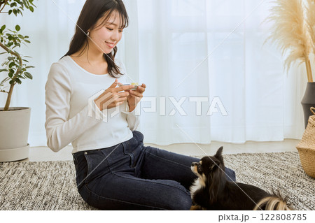 リビングで愛犬と遊ぶ女性 122808785