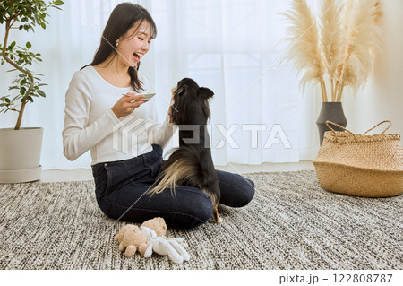 リビングで愛犬と遊ぶ女性 リビングで愛犬と遊ぶ女性 122808787