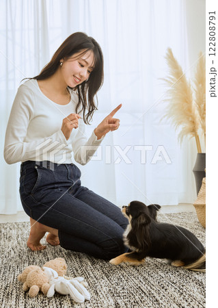 リビングで愛犬と遊ぶ女性 122808791