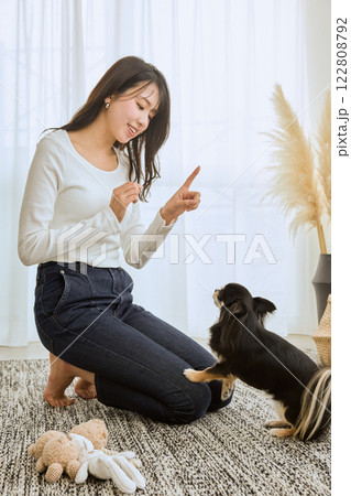 リビングで愛犬と遊ぶ女性 122808792