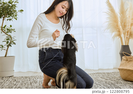 リビングで愛犬と遊ぶ女性 122808795