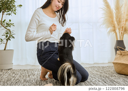 リビングで愛犬と遊ぶ女性 122808796