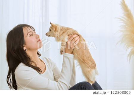 リビングで愛犬と遊ぶ女性 122808809