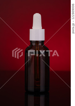 Amber Glass Dropper Bottle with White Cap on Red Background 122809006