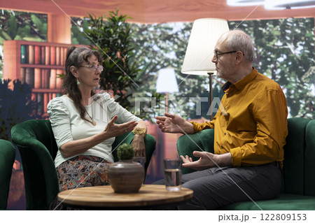 Elderly man and woman enjoying leisure free time at their home, engaging in a joyful conversation and laughing together. Relaxed and healthy aging people, wellness and companionship. Elderly man and woman enjoying leisure free time at their home, engaging in a joyful conversation and laughing together. Relaxed and healthy aging people, wellness and companionship. 122809153