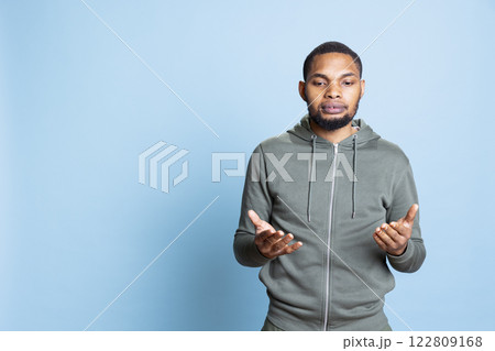 Young religious adult worshipping God for peace and love in studio, posing with prayer hands and showing his belief in Christianity. Portrait of casual person with faith in religion. 122809168