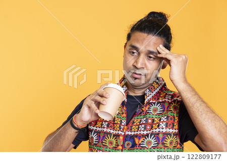 Tired man feeling pain, suffering from headache after sleepless night, drinking coffee. Injured person rubbing head temples, feeling discomforting strain, sipping caffeine drink, studio background Tired man feeling pain, suffering from headache after sleepless night, drinking coffee. Injured person rubbing head temples, feeling discomforting strain, sipping caffeine drink, studio background 122809177