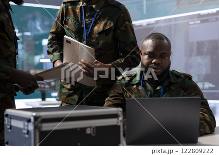 Military analysts in a modern control center power base overseeing reconnaissance tasks, coordinate security protocols and collect real time data for field operations. Control tower activity. 122809222