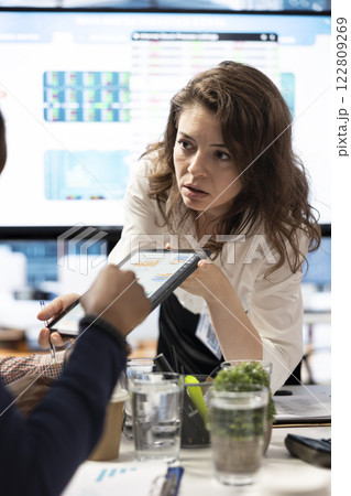 Project manager and staff engaging in a collaborative briefing meeting, using the interactive board and data visualization tools to present potential expansion solutions and enhance outcomes. 122809269