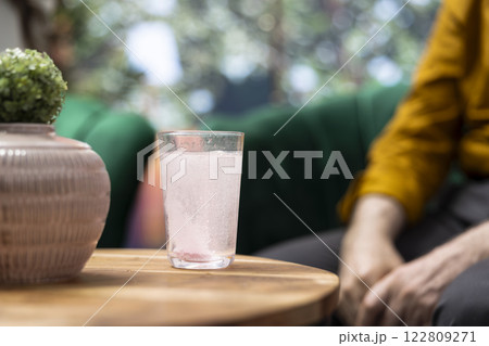 Senior man and woman serving their effervescent supplements with a glass of water, drinking the sparkling vitamins as part of their treatment. Elderly people at home during retirement. Close up. 122809271