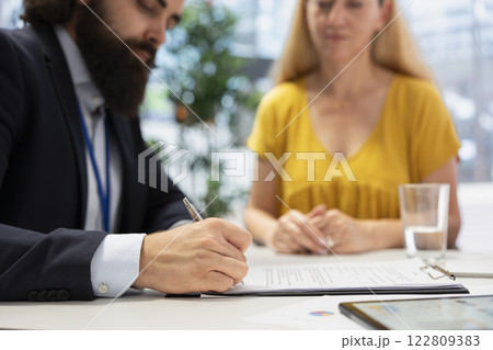 Financial advisor creating reports on investment performance and activity, filling paperwork forms. Close up shot of agent writing documents, developing portfolio maximizing financial gains 122809383