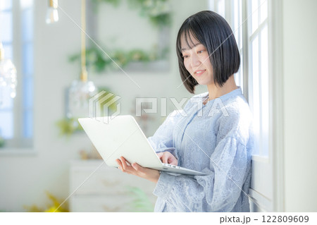 部屋でパソコンを使う若い女性 122809609