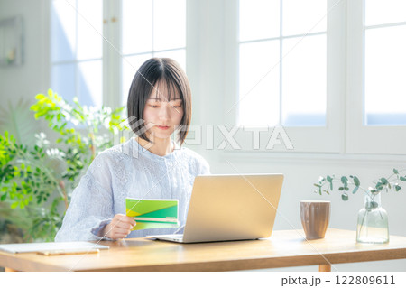 通帳とパソコンを見る女性 122809611