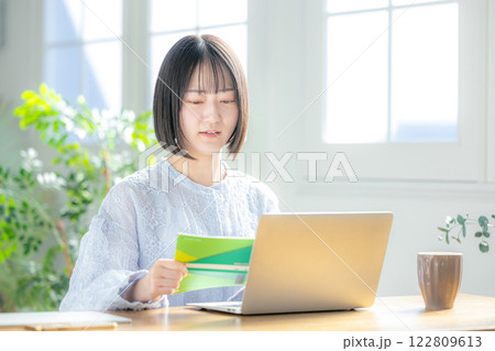 通帳とパソコンを見る女性　困る 122809613