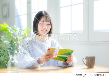 通帳とスマホを見る女性 通帳とスマホを見る女性 122809617