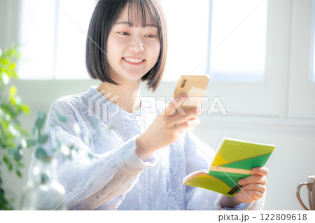 通帳とスマホを見る女性 122809618