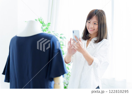 スマートフォンで衣服の撮影をする女性 122810295