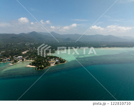 Scenic coastline featuring turquoise waters and a mountain backdrop with clear skies. Ko Pha Ngan, Thailand. 122810710