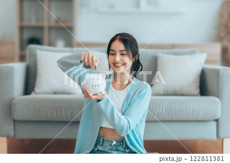 Young Asian woman putting coin in piggy bank. Save money and financial investment Young Asian woman putting coin in piggy bank. Save money and financial investment 122811381