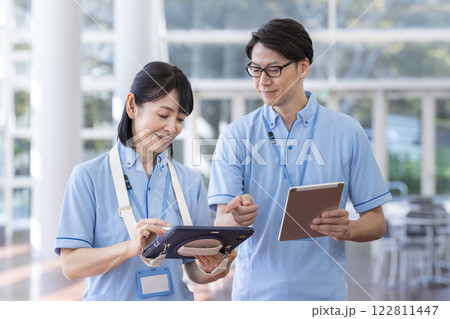 タブレットを見ながら打ち合わせをする施設スタッフ 122811447