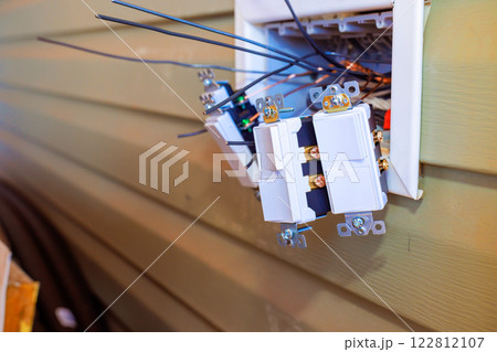 Technicians are installing multiple electrical light switch on wall in home, working carefully with wires tools. Technicians are installing multiple electrical light switch on wall in home, working carefully with wires tools. 122812107