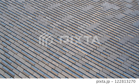Modern Architectural Texture - A dynamic pattern of staggered metallic tiles reflecting natural light. Perfect for design inspiration, urban architecture branding, or construction material concepts 122813270