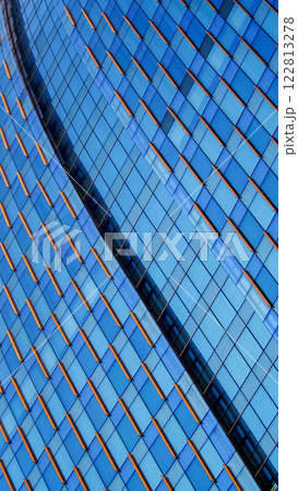 A modern facade with a blue glass grid and vibrant orange accents creates dynamic energy and visual contrast, enhanced by its diagonal orientation 122813278