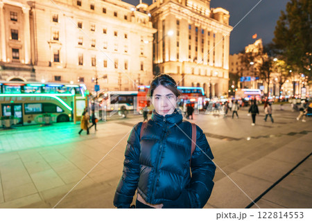 woman traveler visiting in Shanghai, China. Happy Female Tourist sightseeing Shanghai view in The Bund of Shanghai at night. landmark and popular for tourism attractions. Travel and Vacation concept 122814553