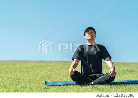芝生・草原で瞑想するスポーツウェア姿の中年アジア人男性 芝生・草原で瞑想するスポーツウェア姿の中年アジア人男性 122815396