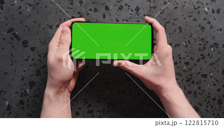 Top view man hand show smartphone with green screen on concrete background Top view man hand show smartphone with green screen on concrete background 122815710