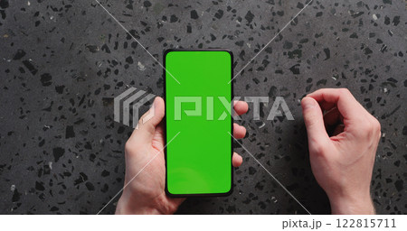 Top view man hand show smartphone with green screen on concrete background Top view man hand show smartphone with green screen on concrete background 122815711