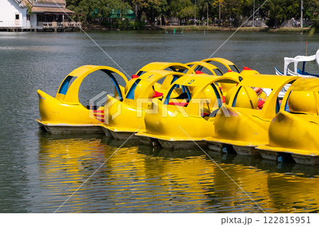 Charming yellow paddle boats ready for fun at scenic lake nature water activity tranquil viewpoint 122815951