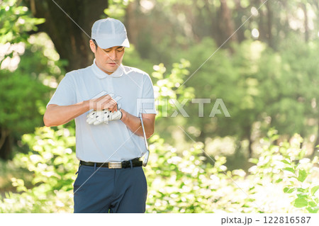 新緑の中でゴルフウェアを着た男性ゴルファー 122816587