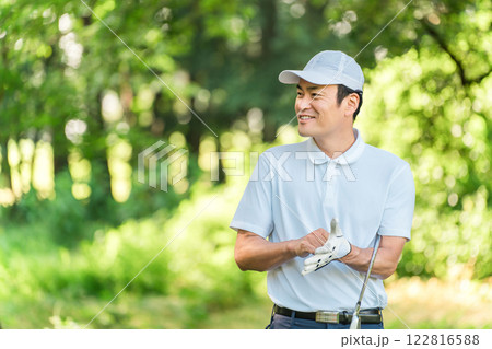 新緑の中でゴルフウェアを着た男性ゴルファー 122816588
