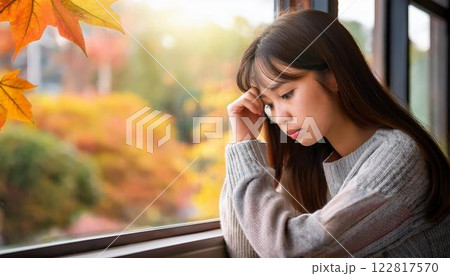 秋の窓辺で物思いにふける少女 | 季節の移ろいと切ない気持ち 122817570