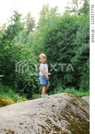 Happy Child Exploring Nature While Standing On Large Rock Happy Child Exploring Nature While Standing On Large Rock 122817736