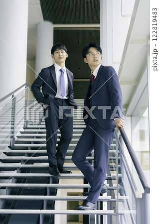 オフィスビルの階段に立つ若いビジネスマン2人のポートレート　縦位置 122819483