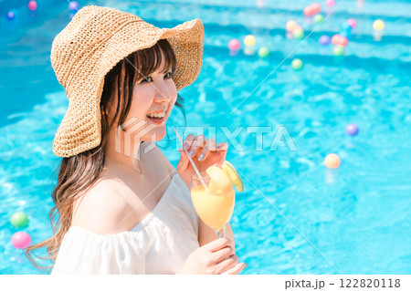 プールサイドでトロピカルジュースを飲む若いアジア人女性（リゾート・バカンス・バケーション） 122820118