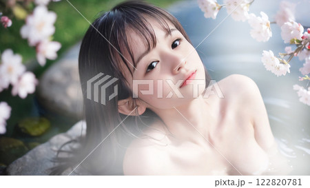 桜の咲く温泉露天風呂に入浴中の若い女性 122820781