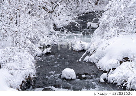白銀の雪に包まれた東北地方の静寂な冬の渓流の風景 122821520