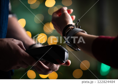 Girl Paying Bill With Watch Using Wireless Pos Terminal During Christmas, Waiter Processing Payment Girl Paying Bill With Watch Using Wireless Pos Terminal During Christmas, Waiter Processing Payment 122824484