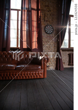 Windows at empty Library room with a brick wall. Leather sofa in a vintage style. The furniture in the room. Dark brown interior Windows at empty Library room with a brick wall. Leather sofa in a vintage style. The furniture in the room. Dark brown interior 122824508