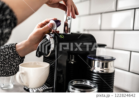 Girl hand put capsule to coffee machine closeup. Woman preparing italian caffeine beverage using professional espresso maker Girl hand put capsule to coffee machine closeup. Woman preparing italian caffeine beverage using professional espresso maker 122824642
