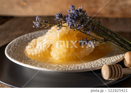 Honey and honeycombs on a white plate. Sweet food in a bowl on the table. A product of beekeeping 122825421