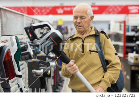 Elderly man choosing Upright Vacuum hoover in showroom of electrical appliance store Elderly man choosing Upright Vacuum hoover in showroom of electrical appliance store 122825722